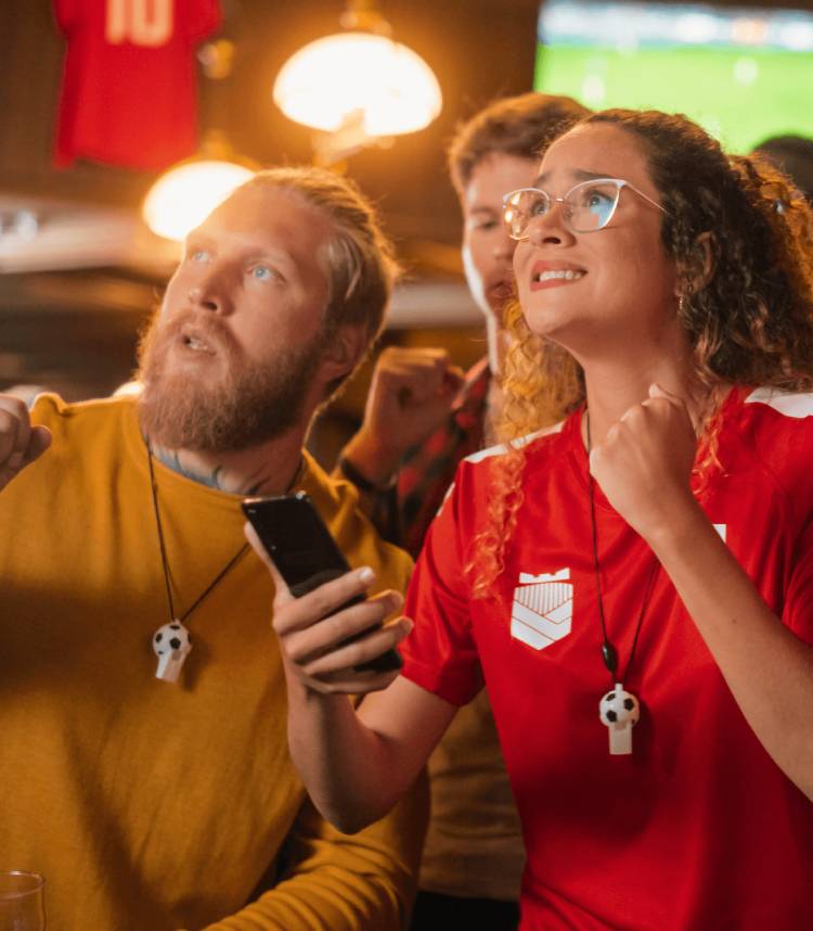 Sports fans cheering at a broadcast while tracking game information on mobile to show omnichannel engagement